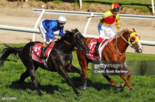 Jockey Michael Walker riding Mighty Boss celebrates as he wins race 8 the Ladbrokes Caulfield Guineas as jockey Damian Lane riding Kementari runs...