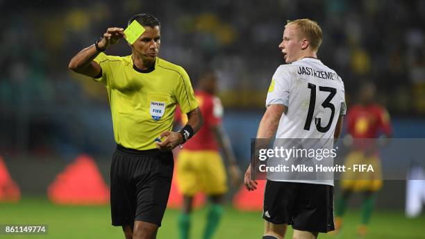 Referee John Pitti of Panama shows the yellow card to Dennis Jastrzembski of Germany during the FIFA U-17 World Cup India 2017 group C match between...