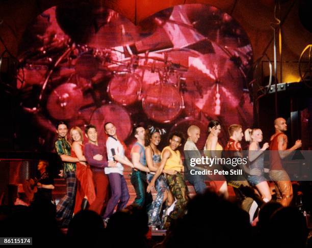 Photo of SPICE GIRLS, Group performing live on stage with male dancers L-R Geri Halliwell, Melanie Chisholm , Melanie Brown , Victoria Adams abd Emma...