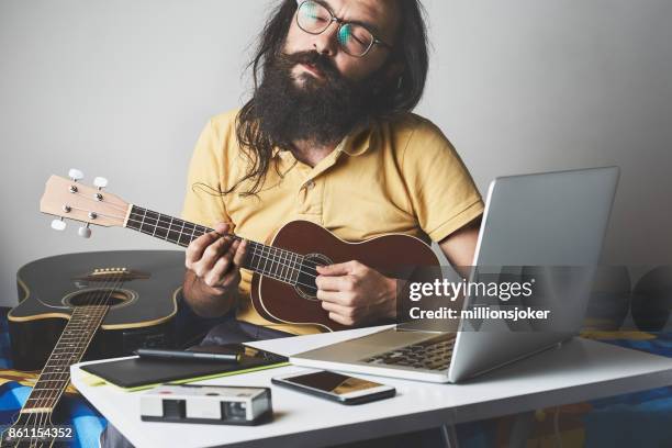 de man is bezig met een baan van de opname in de kamer en de ukulele spelen - edm stockfoto's en -beelden