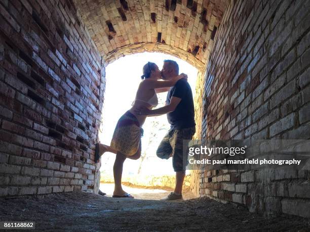 mature couple kissing in small tunnel - calella de palafrugell photos et images de collection