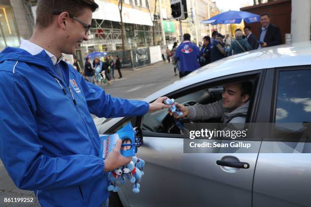 An election campaign worker of the right-wing Austria Freedom Party distributes pamphlets and party mechandise to a passing motorist on October 14,...