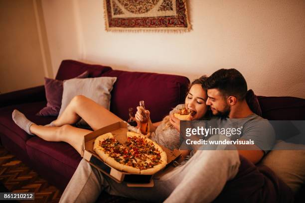 young hipster couple relaxing on the sofa eating pizza - get out film 2017 stock pictures, royalty-free photos & images
