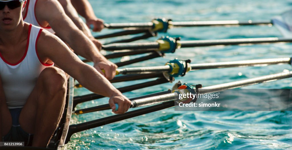 Quatre athlètes masculins d’aviron sur le lac en fin d’après-midi