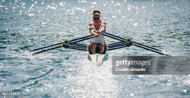 zwei männliche athleten am späten nachmittag über see rudern - rennrudern stock-fotos und bilder