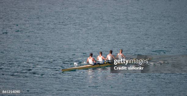 quatre athlètes masculins d’aviron sur le lac en fin d’après-midi - sweep rowing photos et images de collection