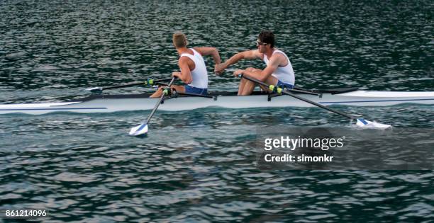 午後遅くにボート湖を渡って 2 つの男子選手 - sweep rowing ストックフォトと画像