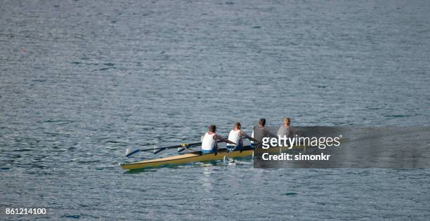 quatre athlètes masculins d’aviron sur le lac en fin d’après-midi - sweep rowing photos et images de collection