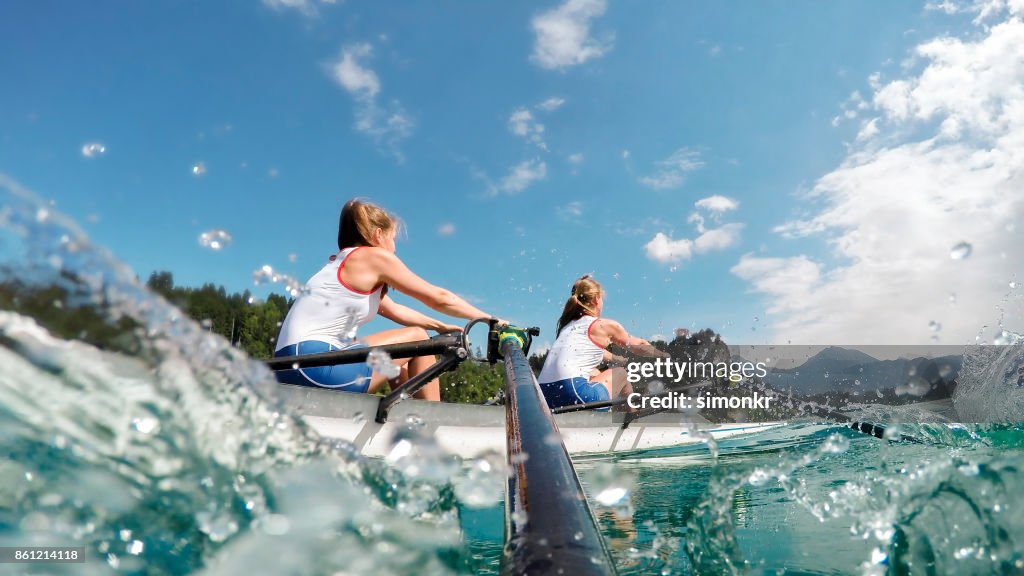 Dois atletas do sexo feminino remo lago no fim da tarde