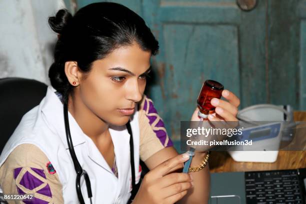 vrouwelijke arts voorbereiding injectie in kliniek - india lab stockfoto's en -beelden