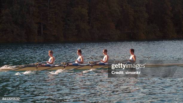 午後遅くにボート湖を渡って 4 つの男性選手 - sweep rowing ストックフォトと画像