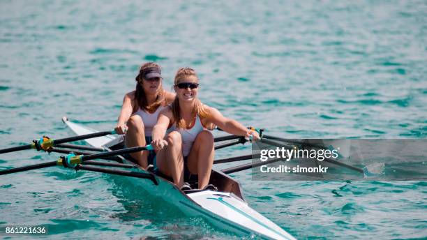 two female athletes sculling across lake - female rower stock pictures, royalty-free photos & images
