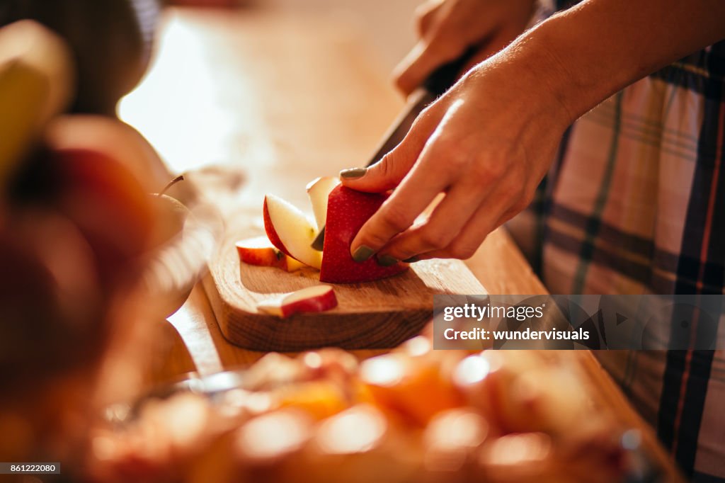 Las manos de la mujer joven corte una manzana en madera cortan madera