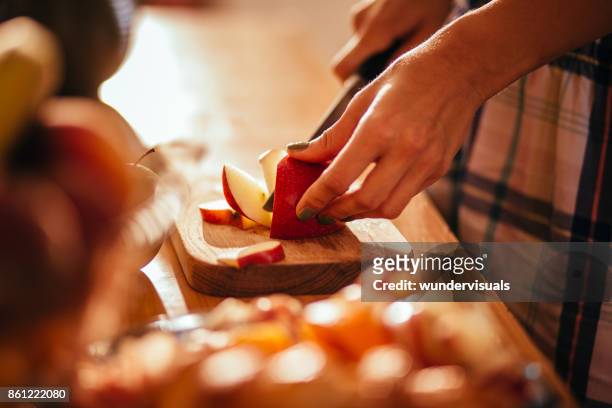 young woman's hands cutting an apple on wooden cut board - slashes stock pictures, royalty-free photos & images