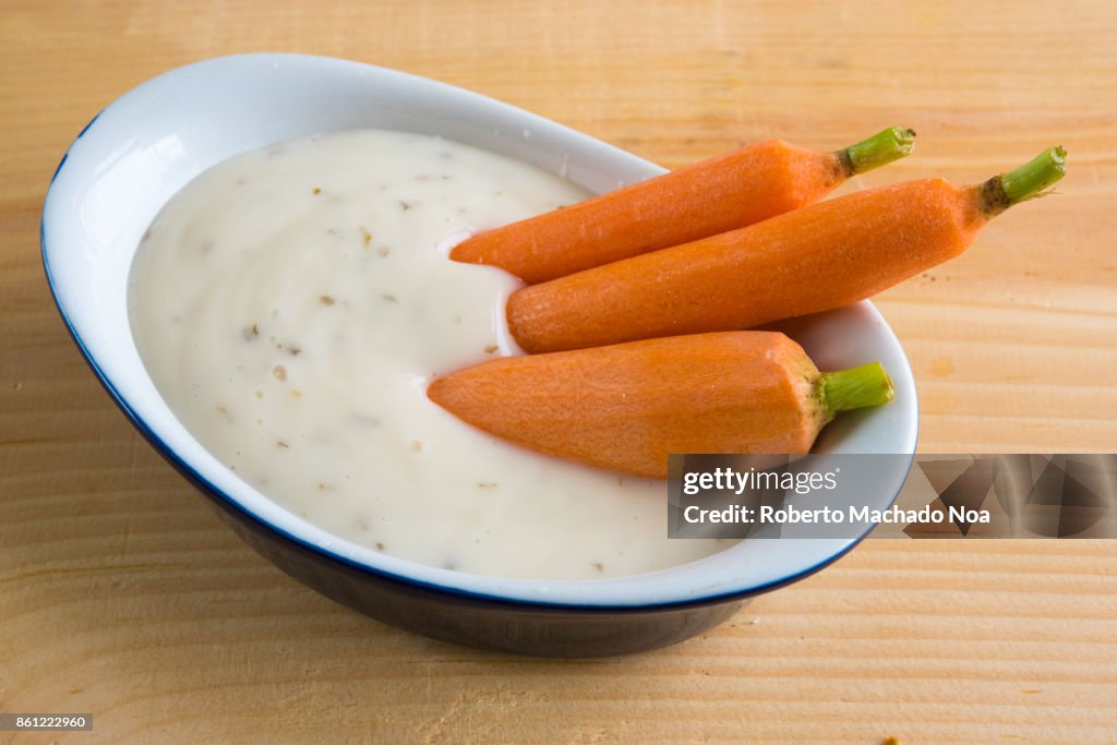 Healthy eating: small raw carrots or natural baby carrots in a small recipient full of ranch dressing