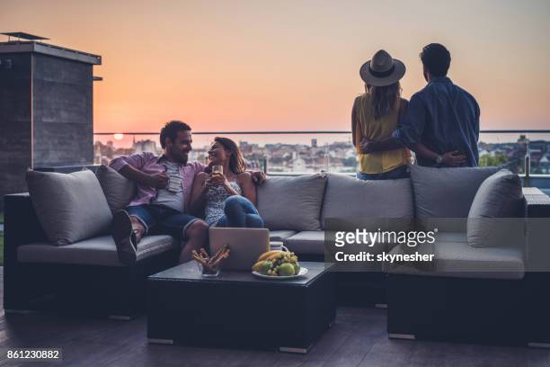 young couples relaxing on a penthouse patio at sunrise. - coffee on patio stock pictures, royalty-free photos & images