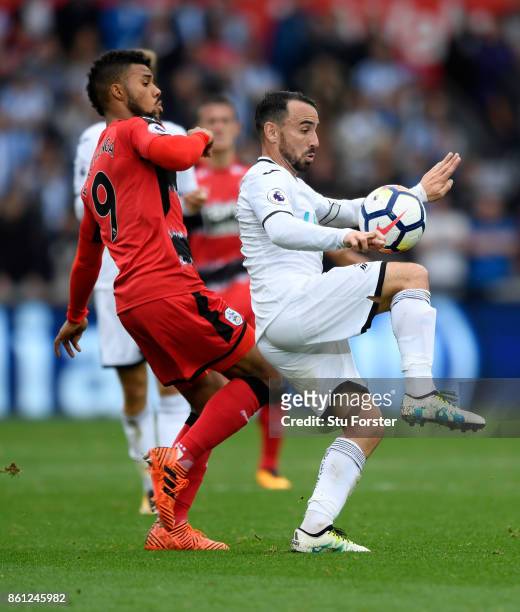 Town player Elias Kachunga challenges Leon Britton of Swansea during the Premier League match between Swansea City and Huddersfield Town at Liberty...