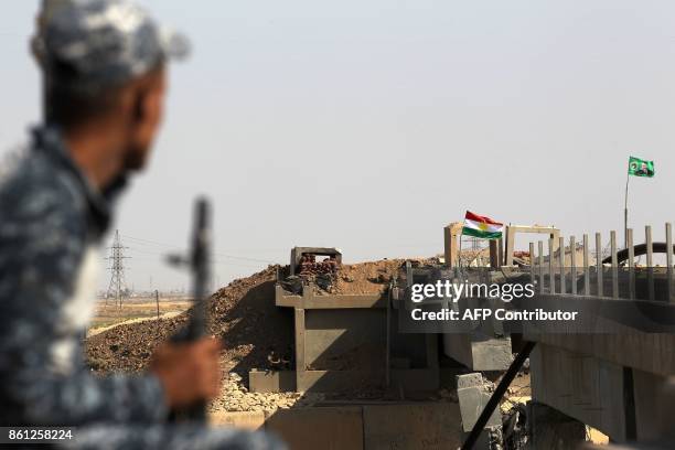 Member of the Iraqi forces sits near a bridge across from Kurdish peshmerga positions on October 14 on the southern outskirts of Kirkuk. Thousands of...