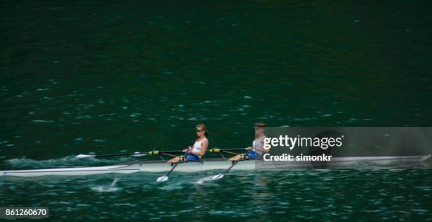 zwei weibliche athleten am späten nachmittag über see rudern - rennrudern stock-fotos und bilder