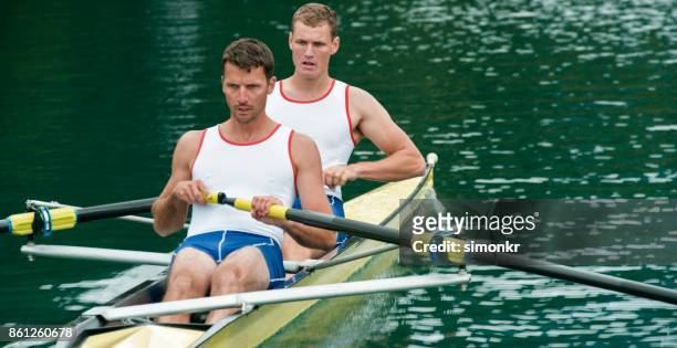 午後遅くにボート湖を渡って 2 つの男子選手 - sweep rowing ストックフォトと画像