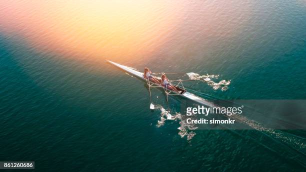 dos atletas de remo en el lago sol - remo de competición fotografías e imágenes de stock