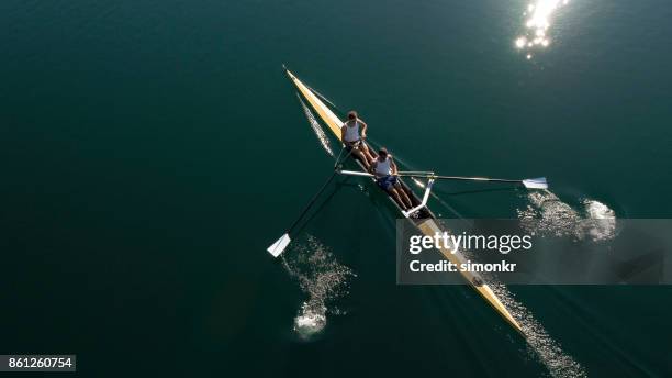 zwei männliche athleten ruderern auf see in der sonne - rennrudern stock-fotos und bilder