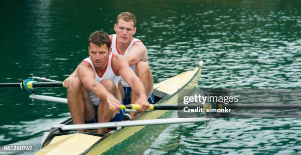 två manliga idrottare rodd över sjön i sena eftermiddagen - sweep rowing bildbanksfoton och bilder
