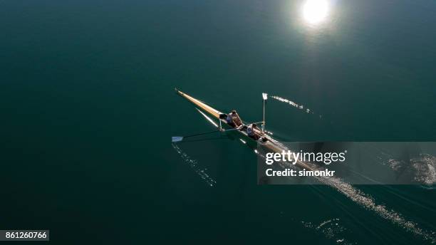 dos atletas masculinos remar en el lago sol - remo de punta fotografías e imágenes de stock