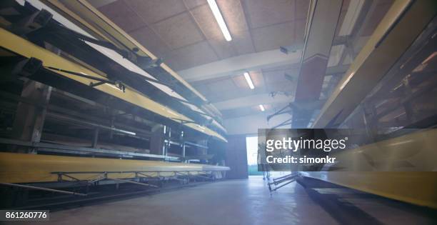 two male athletes taking sweep oar boat out of boathouse - sweep rowing stock pictures, royalty-free photos & images