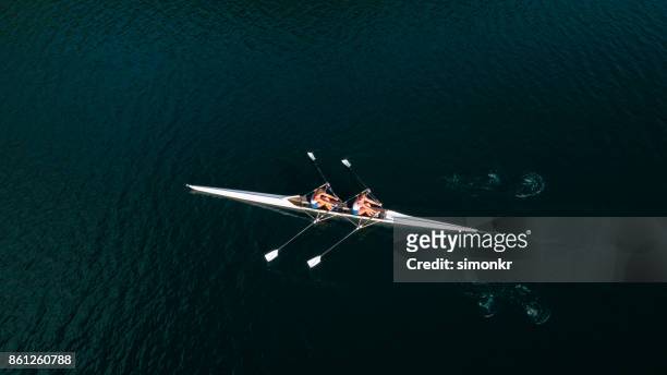 dos atletas de remo en el lago sol - remo de punta fotografías e imágenes de stock
