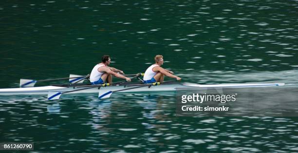 två manliga idrottare rodd över sjön i sena eftermiddagen - sweep rowing bildbanksfoton och bilder