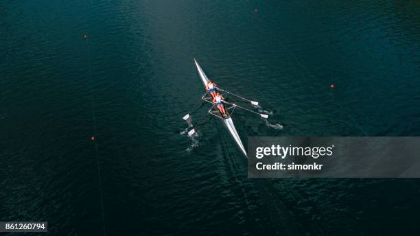 due atlete che sculling sul lago sotto il sole - sweep rowing foto e immagini stock