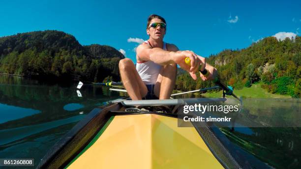 male athlete in yellow coxless pair rowing in sunshine - sweep rowing stock pictures, royalty-free photos & images