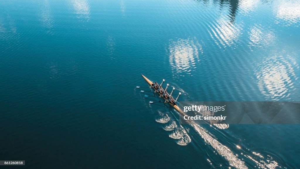 Cuatro atletas masculinos remar en el lago sol