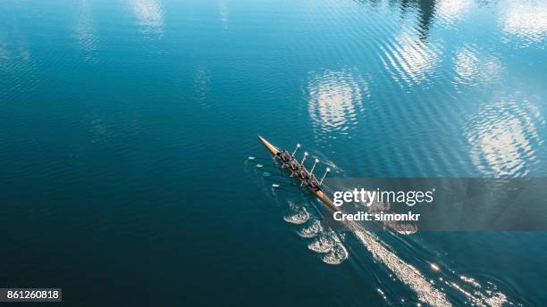 cuatro atletas masculinos remar en el lago sol - remo de competición fotografías e imágenes de stock