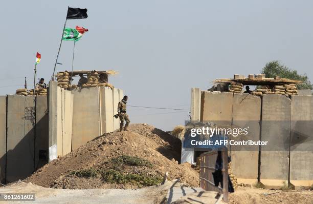 Kurdish peshmerga fighters hold a position on a river bank across from Iraqi forces on October 14 on the southern outskirts of Kirkuk. Thousands of...