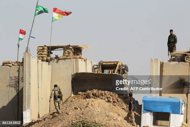 Kurdish peshmerga fighters hold a position on a river bank across from Iraqi forces on October 14 on the southern outskirts of Kirkuk. Thousands of...