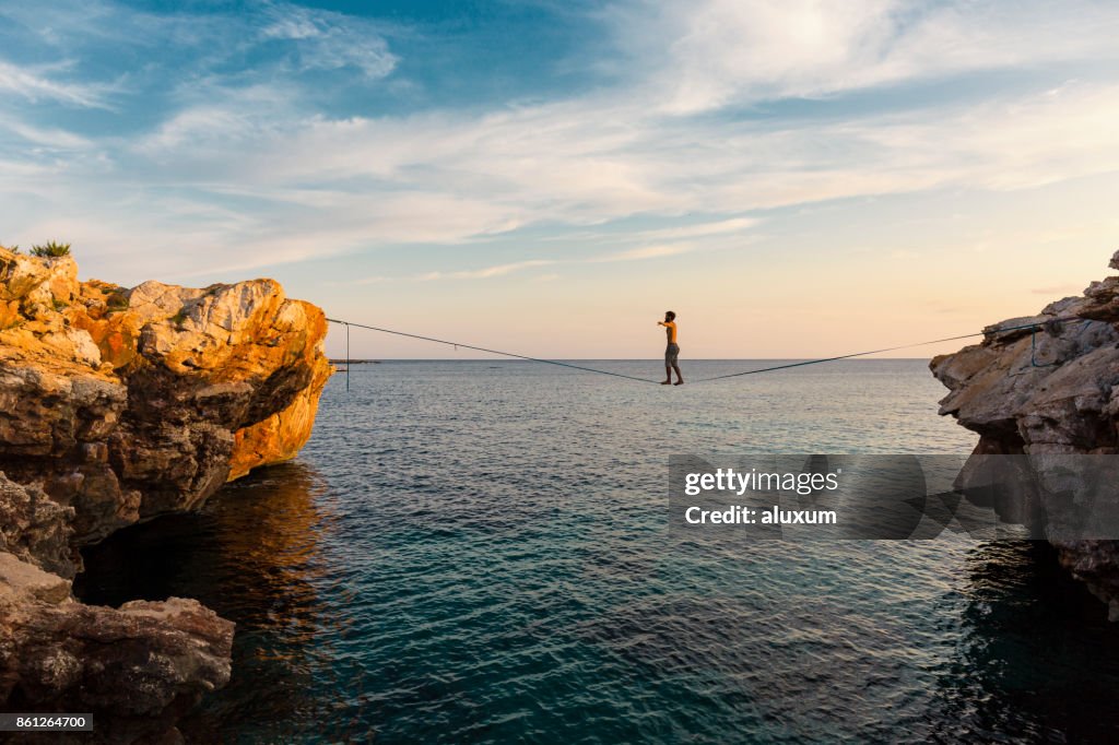 Hombre practicando slackline sobre el mar