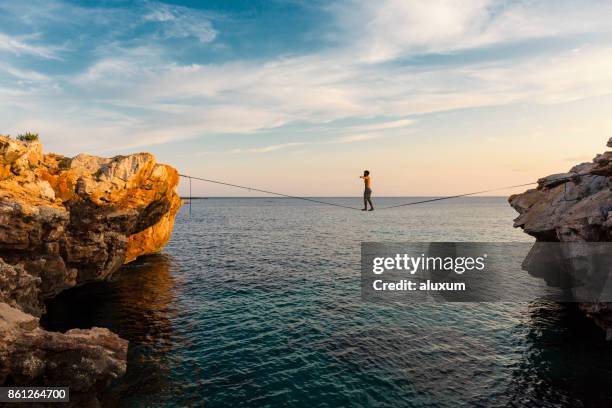 homem praticando slackline sobre o mar - corda bamba - fotografias e filmes do acervo