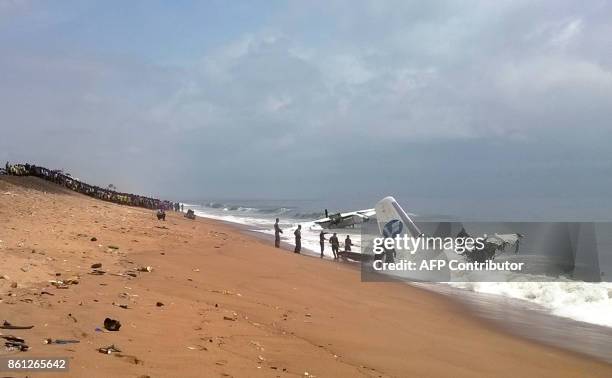 Picture taken with a mobile phone shows members of rescue services standing on the beach of Port-Bouet in Abidjan as they look at the wreckage of a...