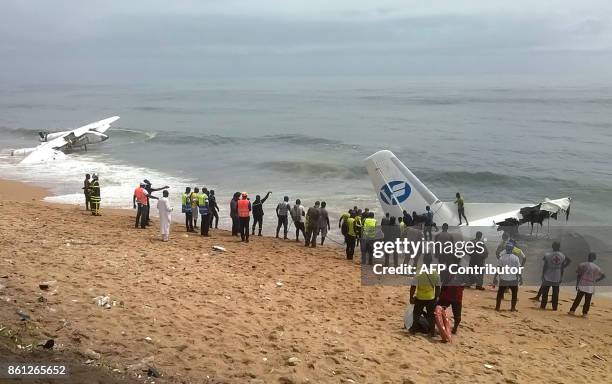 Picture taken with a mobile phone shows members of rescue services standing on the beach of Port-Bouet in Abidjan as they look at the wreckage of a...