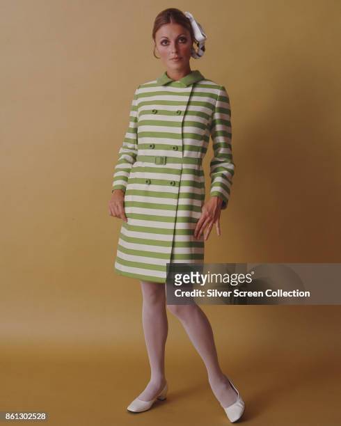 Portrait of American model and actress Sharon Tate , her thumbs in the pockets her horizontally striped green and white dress, as she poses against a...