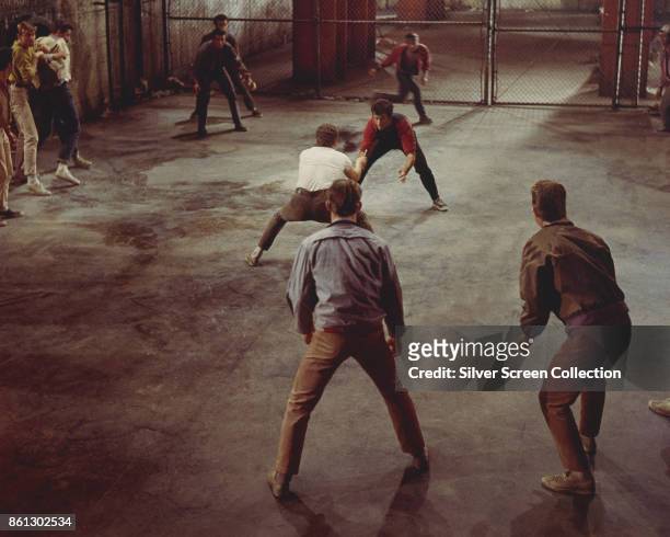 American actors George Chakiris and Russ Tamblyn , surrounded by cast members, fight in a scene from 'West Side Story' , 1961.
