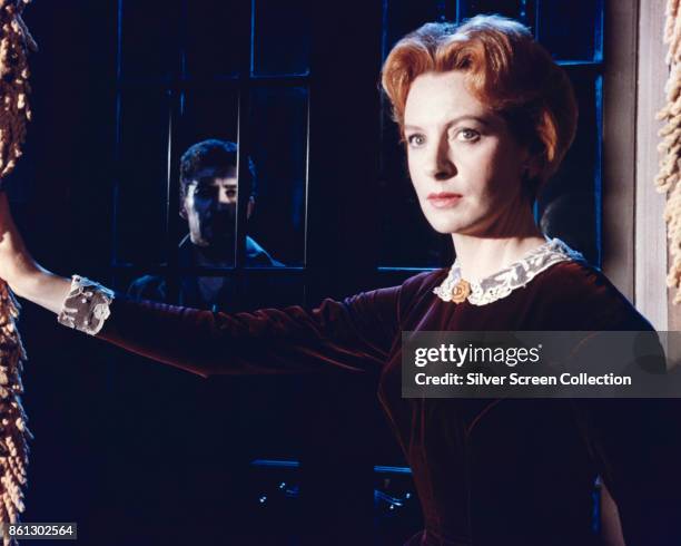 Scottish actress Deborah Kerr behind a rain-splattered window in a scene from 'The Innocents' , England, 1961. Lurking in the shadows behind her is...