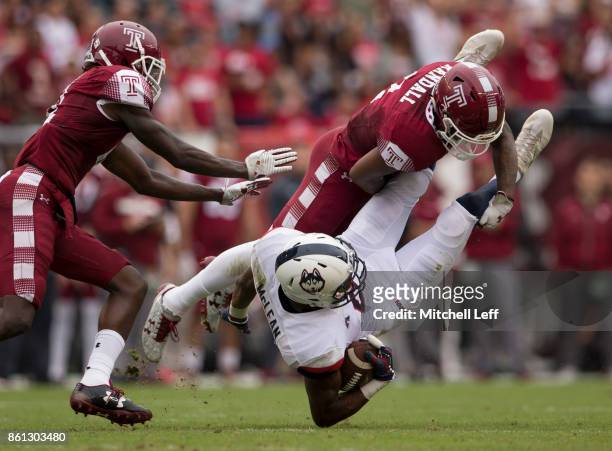 Aaron McLean of the Connecticut Huskies runs with the ball and is tackled by Delvon Randall of the Temple Owls in the second quarter at Lincoln...