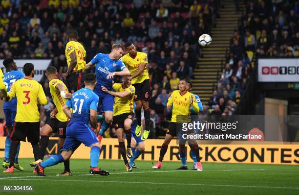 Per Mertesacker outjumps Watford defender Adrian Mariappa to score for Arsenal during the Premier League match between Watford and Arsenal at...