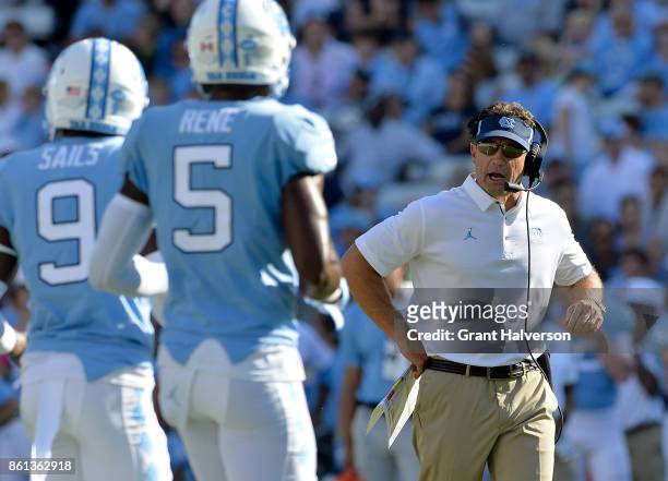 Head coach Larry Fedora talks to K.J. Sails and Patrice Rene of the North Carolina Tar Heels during their game against the Virginia Cavaliers at...