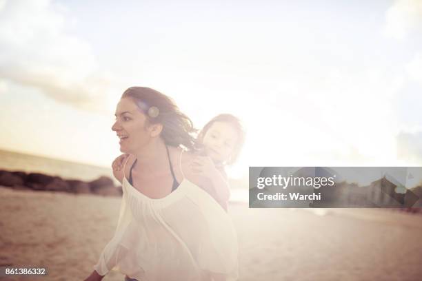 mother playing with her daughter on the beach at sunset - mexican and white baby stock pictures, royalty-free photos & images