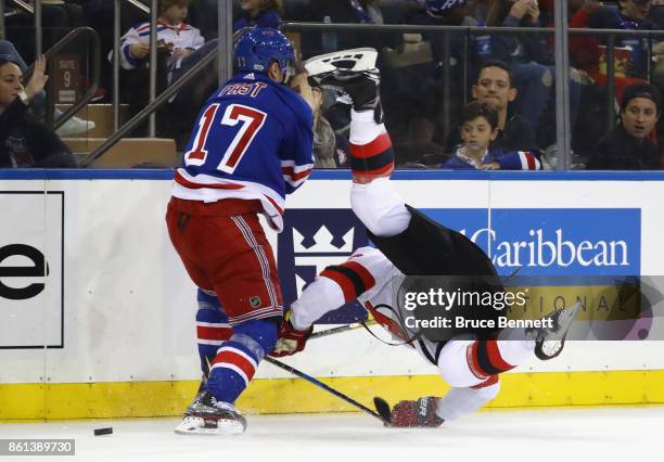 Jesper Fast of the New York Rangers checks Steven Santini of the New Jersey Devils during the first period at Madison Square Garden on October 14,...