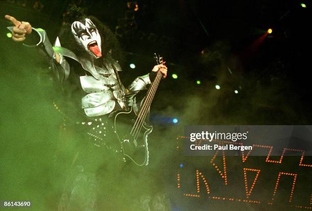 Photo of Gene SIMMONS and KISS; Gene Simmons performing on stage, sticking tongue out, pointing